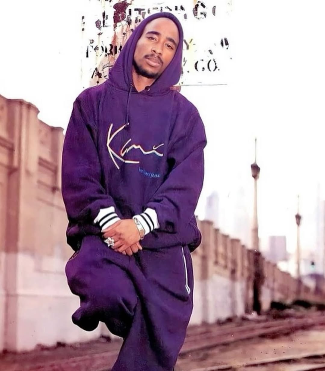 Tupac Shakur v fialovej mikine a teplákoch Karl Kani na streche v meste, 90. roky
